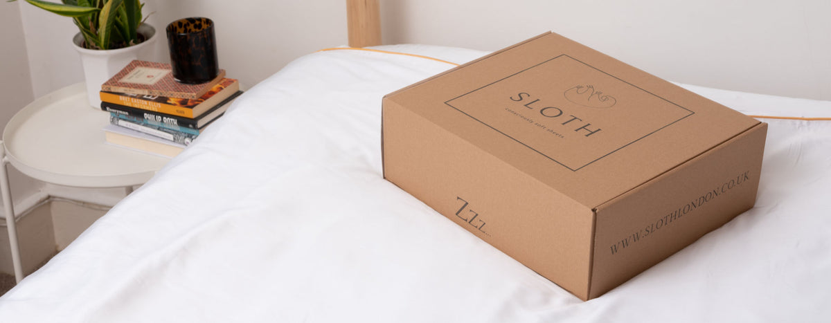 Sloth London bedding and packaging on a white bed